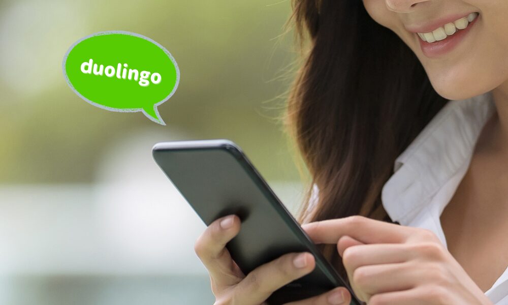 女性が携帯の画面を見ながらDuolingoで英語の勉強を楽しんでいる画像