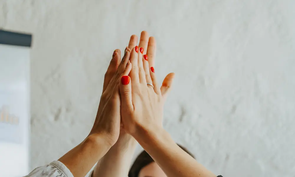 英語を学ぶことで新しい世界に踏み出して達成感を得ているイメージ。友人とハイタッチをしている。