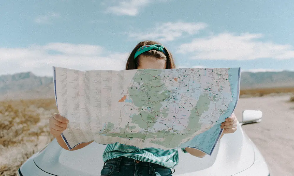 女性が地図を見て目的地までの行き方をチェックしている。英語を学ぶ目的に合わせて英文法を学べるイメージ。