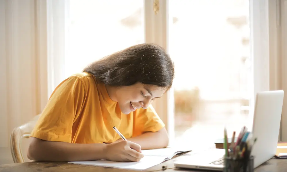 英語日記を楽しく書くコツのイメージ。笑顔で日記を書いている。