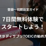 英語の辞書やノートが置かれた机で、スマホを見ながらTOEICの勉強をしている女性