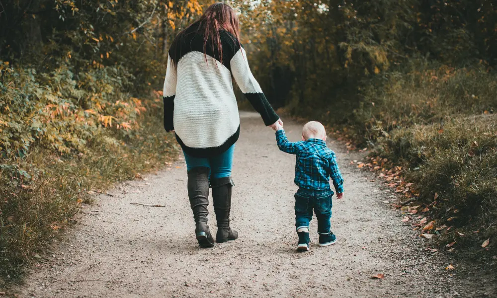 小さな子どもと母親が並んで歩く後ろ姿。ゆっくり進む歩みの象徴的なシーン。